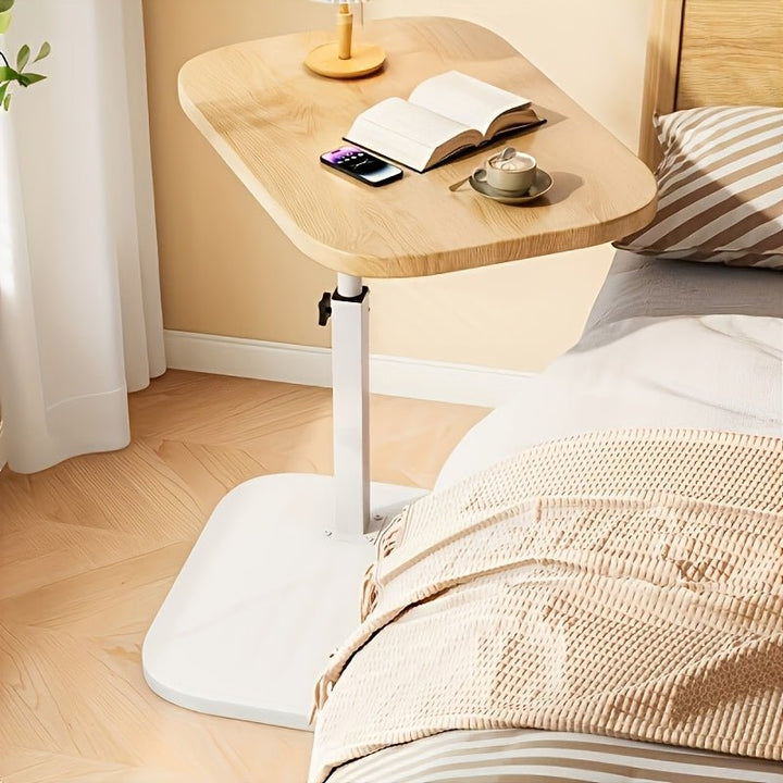 White adjustable side table set up next to a cozy bedroom bed
