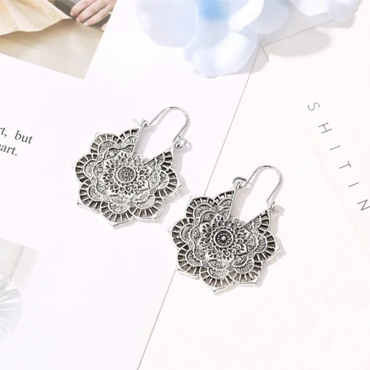 Vintage silver lotus mandala earrings laid flat on a decorative white surface