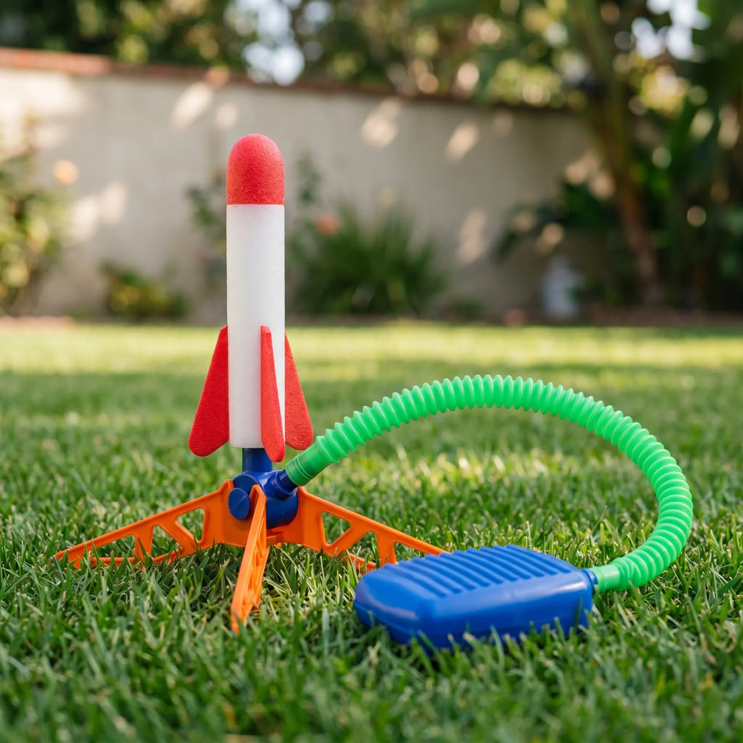 Air powered rocket toy set with tripod base, green air tube, and blue foot pump on grass