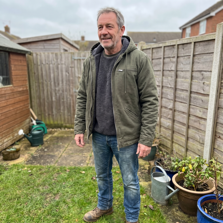 Man standing in garden wearing green hooded winter jacket