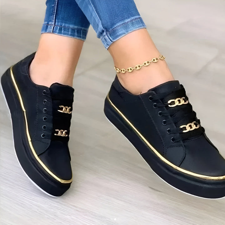 Close-up of black and gold chic comfort sneakers worn with blue jeans