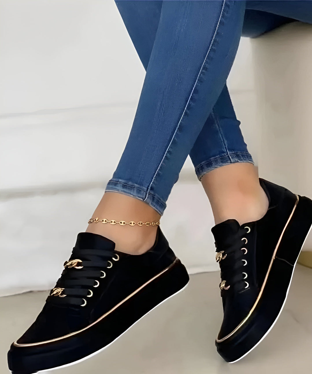 Side view of black sneakers with gold trim paired with denim jeans