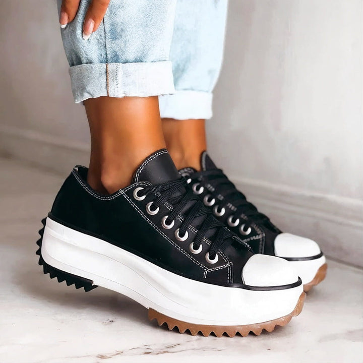 Women's black platform sneakers paired with light wash cuffed jeans