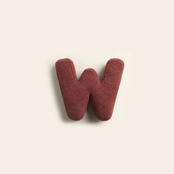 Letter cushion accent pillow resting on fluffy rug