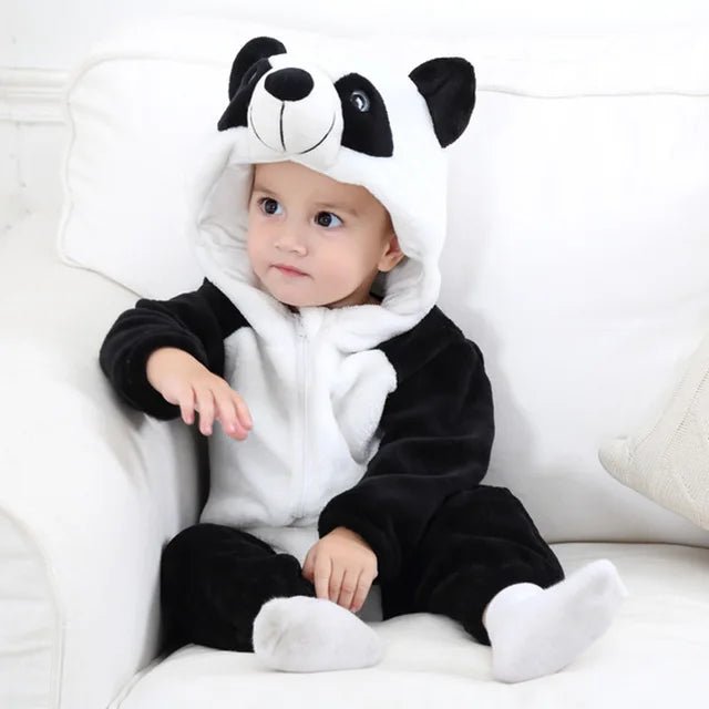 Baby wearing a cute panda animal onesie with a character hood while sitting on a white sofa