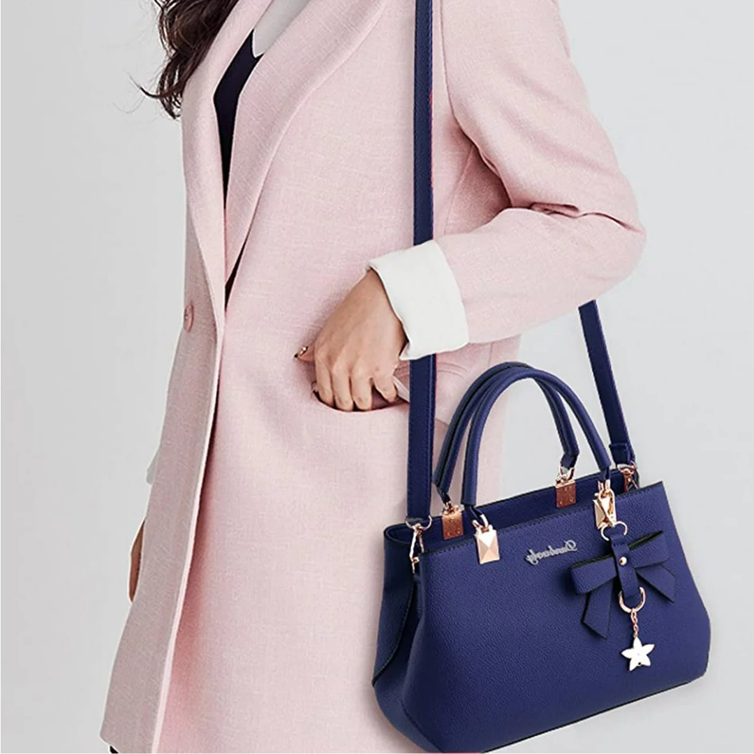 Blue Anna crossbody bag worn by a model in a light pink coat