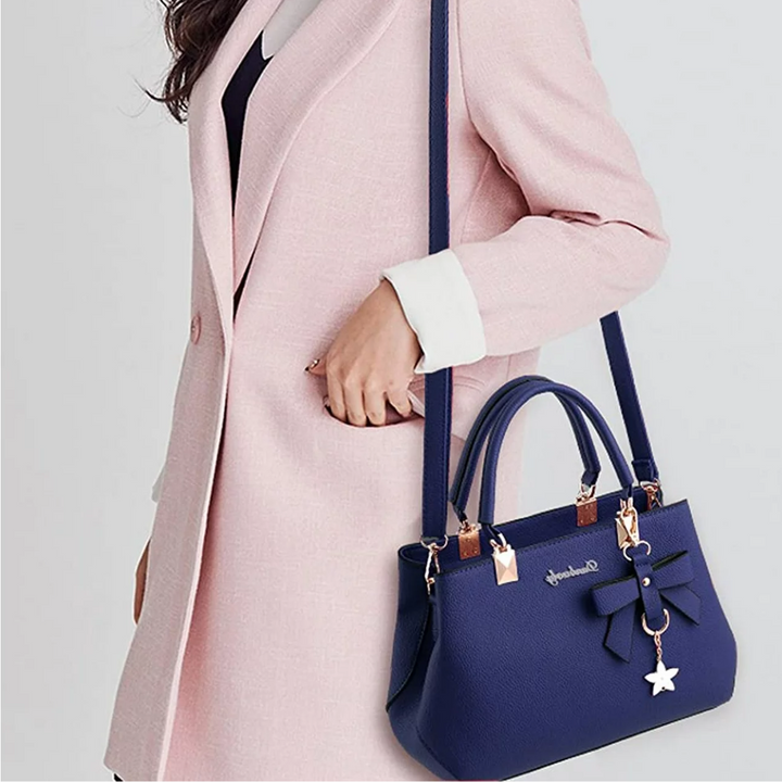Blue Anna crossbody bag worn by a model in a light pink coat