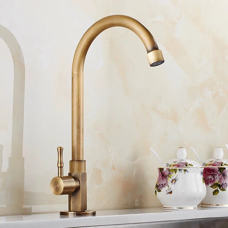 Antique brass swan neck kitchen faucet installed on a white countertop