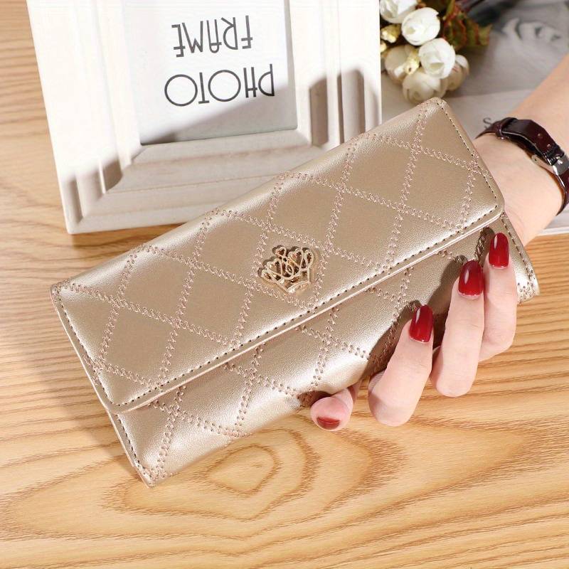 Champagne women's argyle pattern trifold wallet with gold crown accent held in hand
