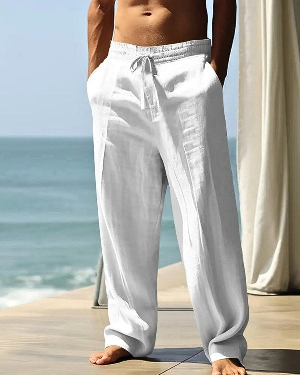 Man wearing white lightweight summer trousers by the sea
