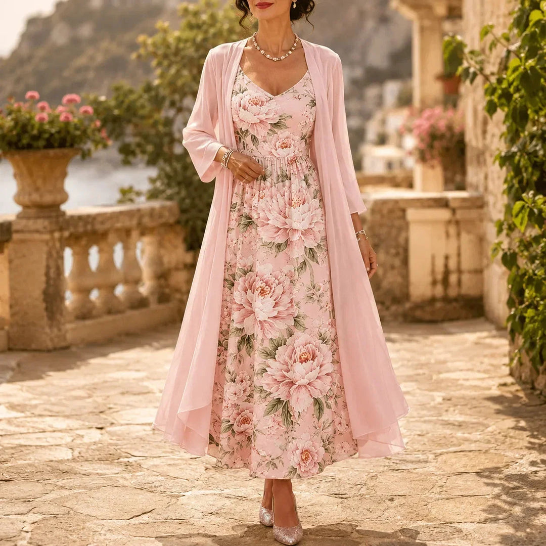 Woman wearing a light pink floral maxi dress and sheer duster set outdoors in a historic courtyard.