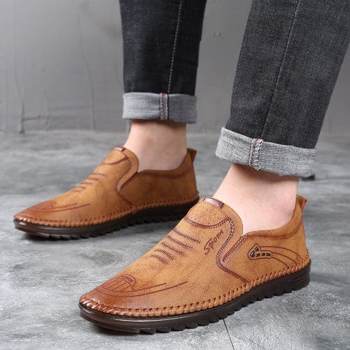 Brown men's orthopedic slip-on loafers worn with dark jeans