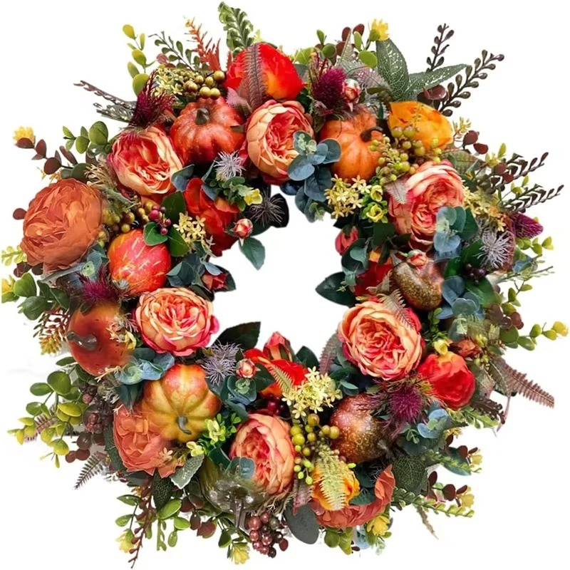 Close-up detail of the autumn wreath featuring vibrant orange peonies and miniature pumpkins.