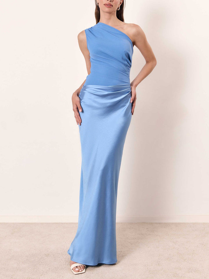 Woman wearing blue one-shoulder pleated maxi dress standing
