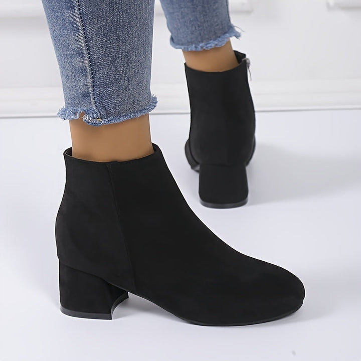 Woman wearing black chelsea ankle boots with low block heel