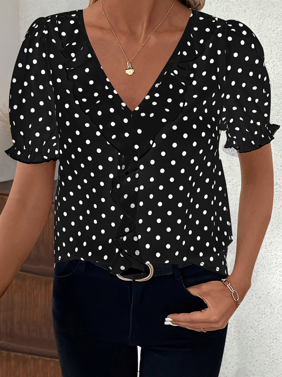 Woman wearing a black short sleeve bubble sleeve blouse with white polka dots and V-neckline