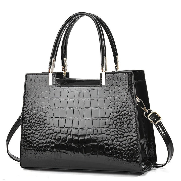 Angle view of the glossy patterned handbag displaying elegant hardware and handles