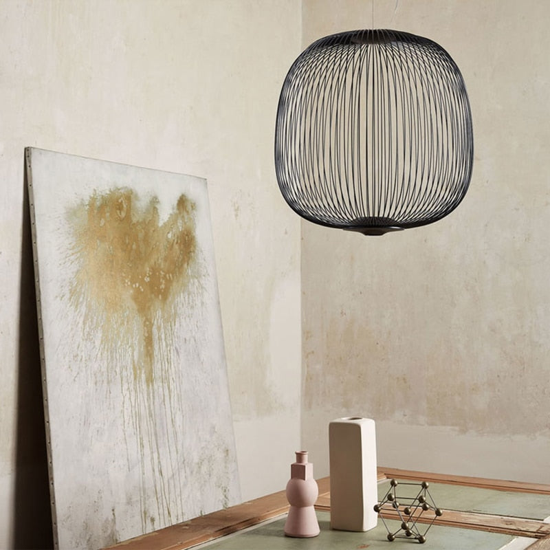 Black iron pendant light hanging in a minimalist room with neutral decor and art