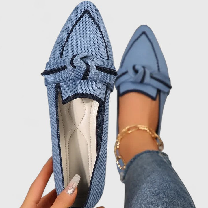 Light blue pointed-toe knot loafers with slip-on design being held up