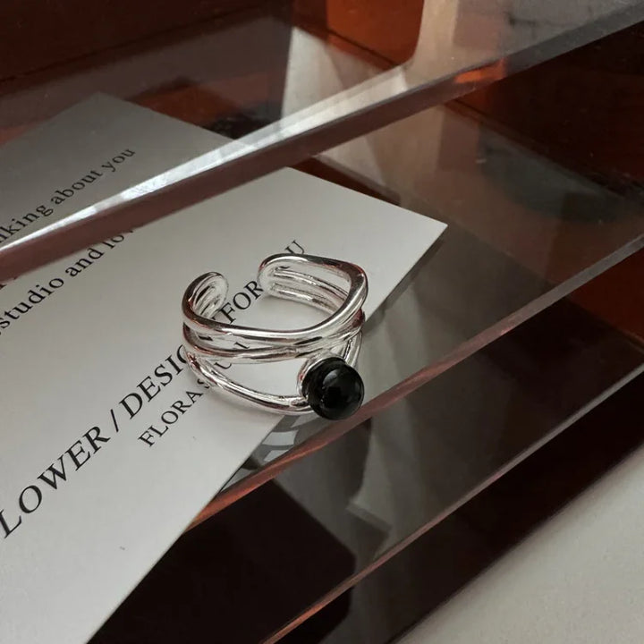 Angle shot of the polished silver multi-line ring on a modern display shelf
