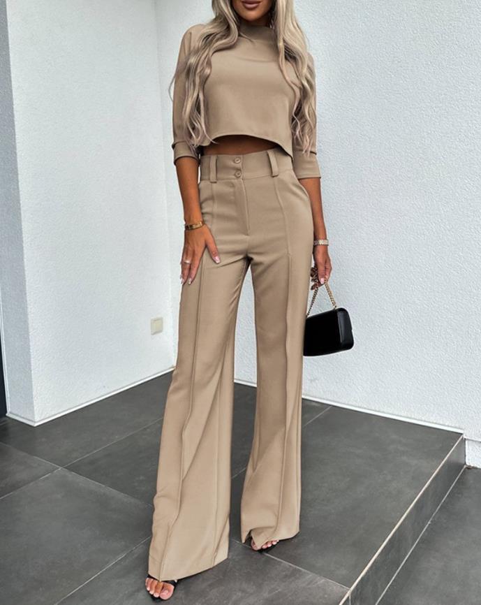 Front view of a woman wearing a stylish beige tailored pants and crop top ensemble