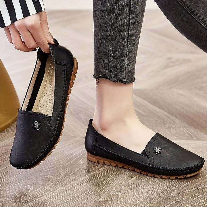 Lifestyle image of a woman walking outdoors while wearing comfortable black slip-on loafers.