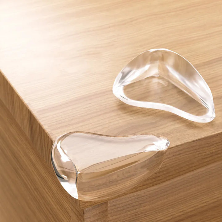 Clear silicone corner protectors installed on a wooden table edge