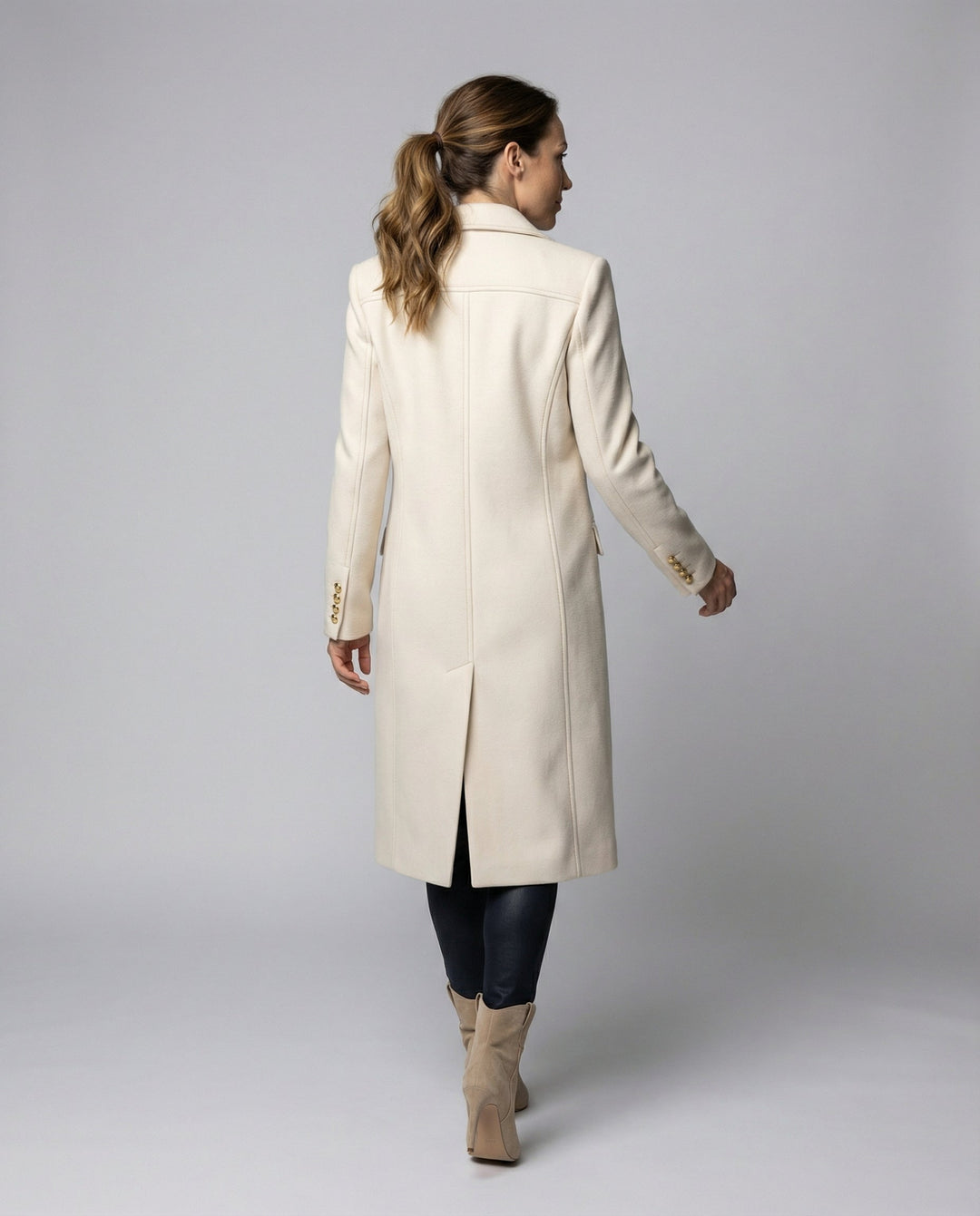 Back view of a woman walking in a tailored beige winter coat