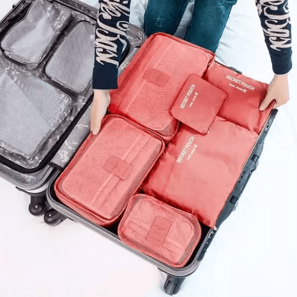 Pink luggage packing organiser set laid out inside an open suitcase