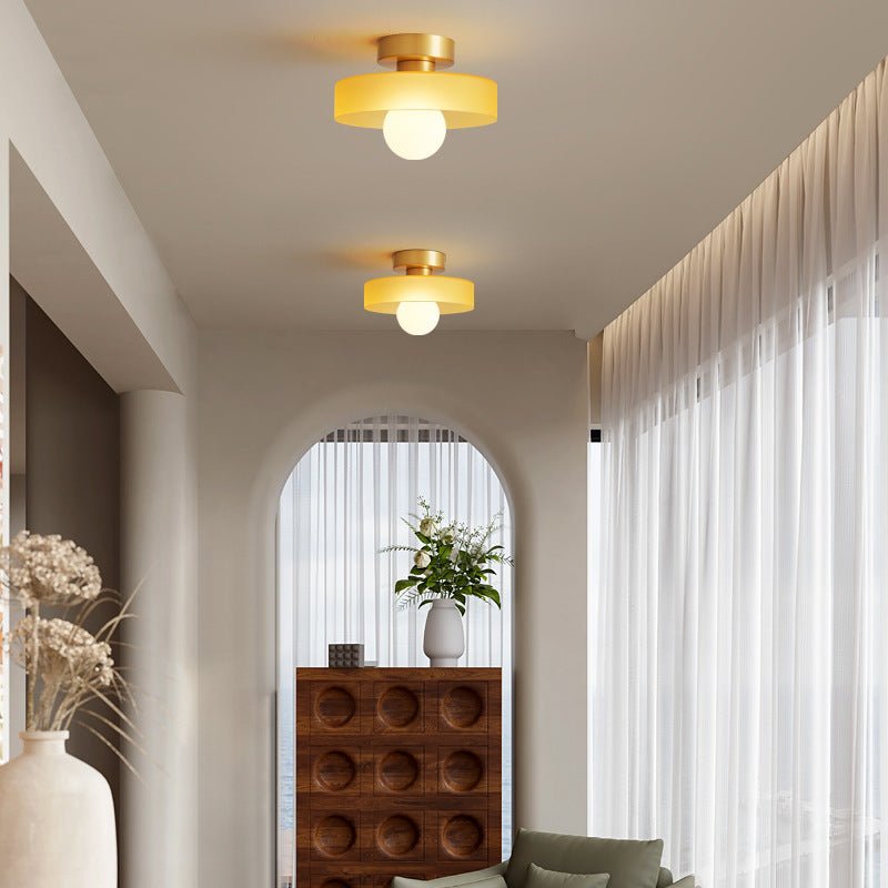 Modern brass ceiling fixture featuring a clean spherical glass shade