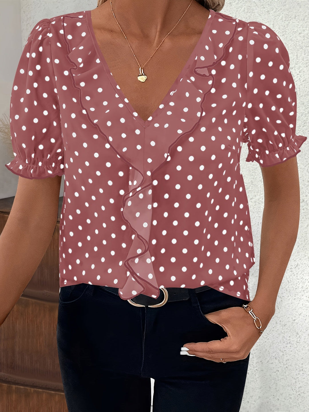 Woman wearing a pink short sleeve bubble sleeve blouse with white polka dots and V-neckline