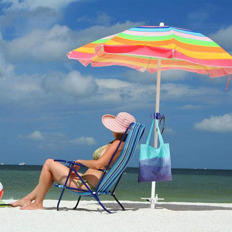 Colorful beach umbrella secured in sand with an anchor next to a lounge chair
