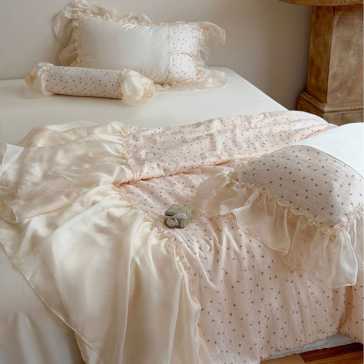 Close up of quilted bed cover and ruffled duvet in soft neutral tones