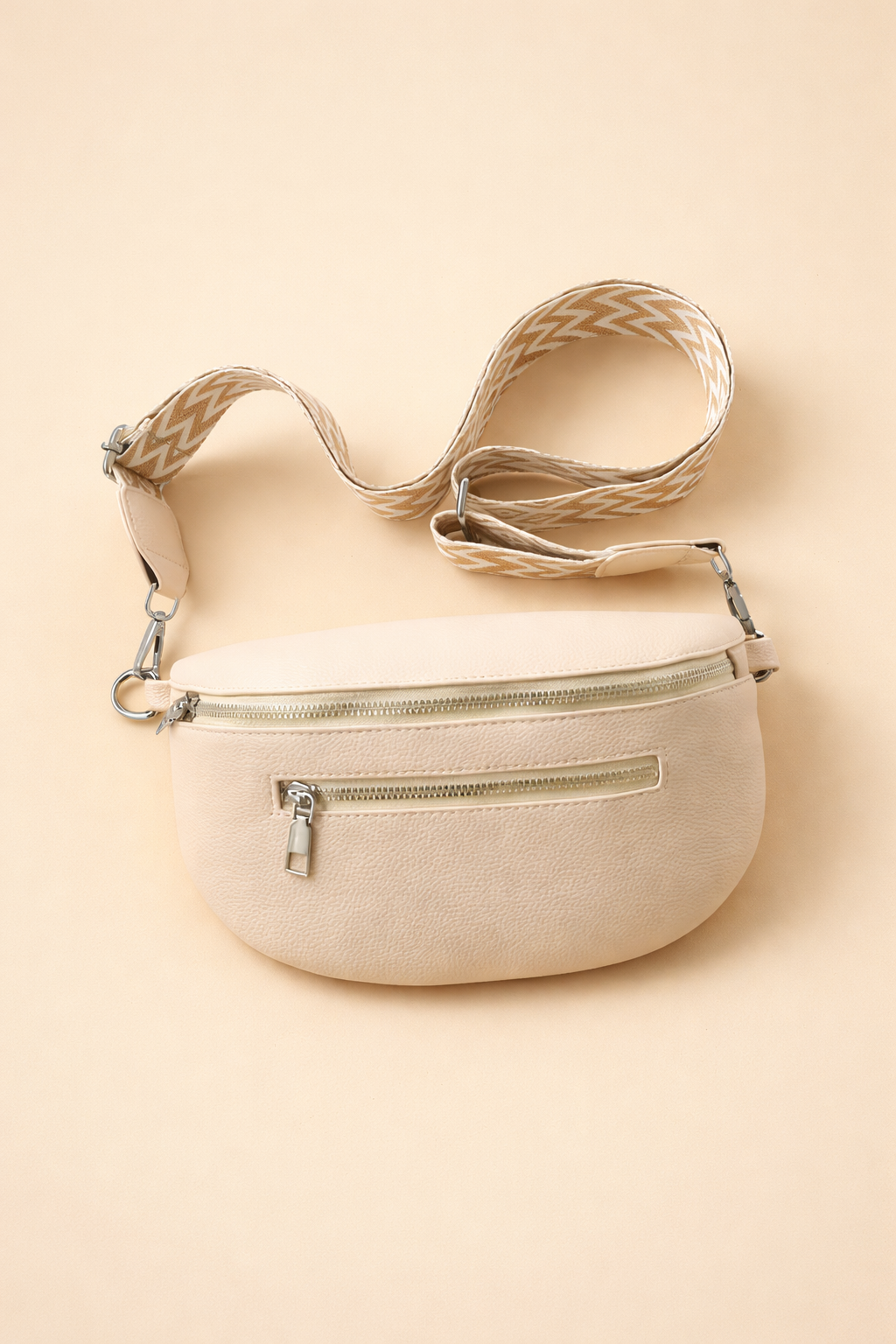 Beige crescent crossbody belt bag with patterned strap