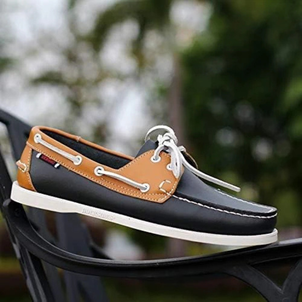 Men's two-tone boat shoe in brown and black resting on a black chair outdoors