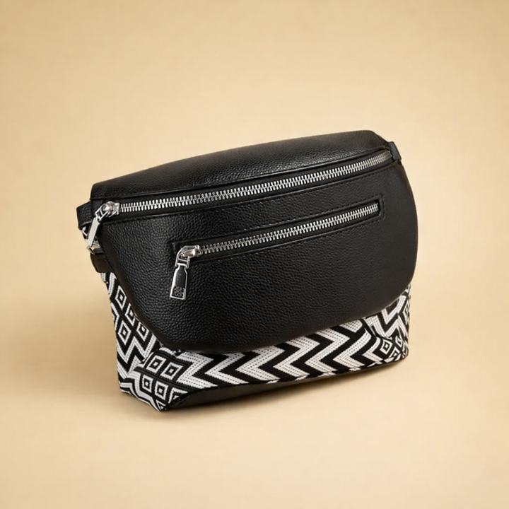 Black crossbody belt bag with patterned strap on neutral background