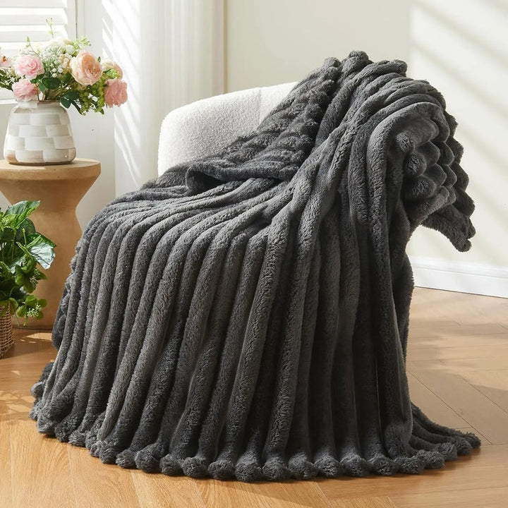Dark grey chunky knit textured throw draped over a modern white armchair