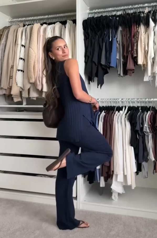 Woman wearing a dark blue ribbed two-piece lounge set posing in front of a closet