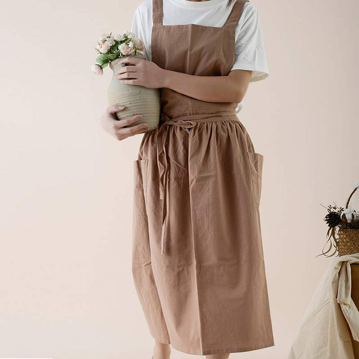 Lifestyle shot of a pink waterproof kitchen apron hanging on a hook