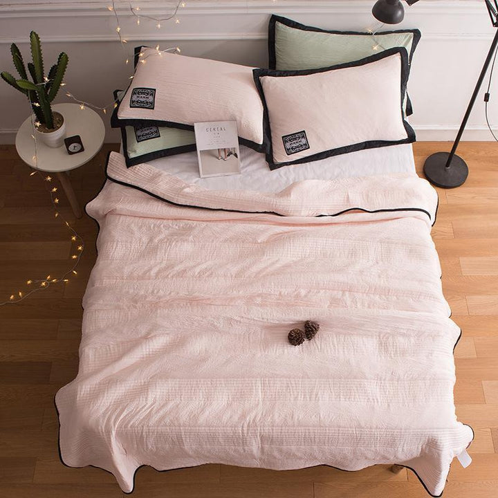 A pink lightweight summer cooling blanket spread neatly across a bed