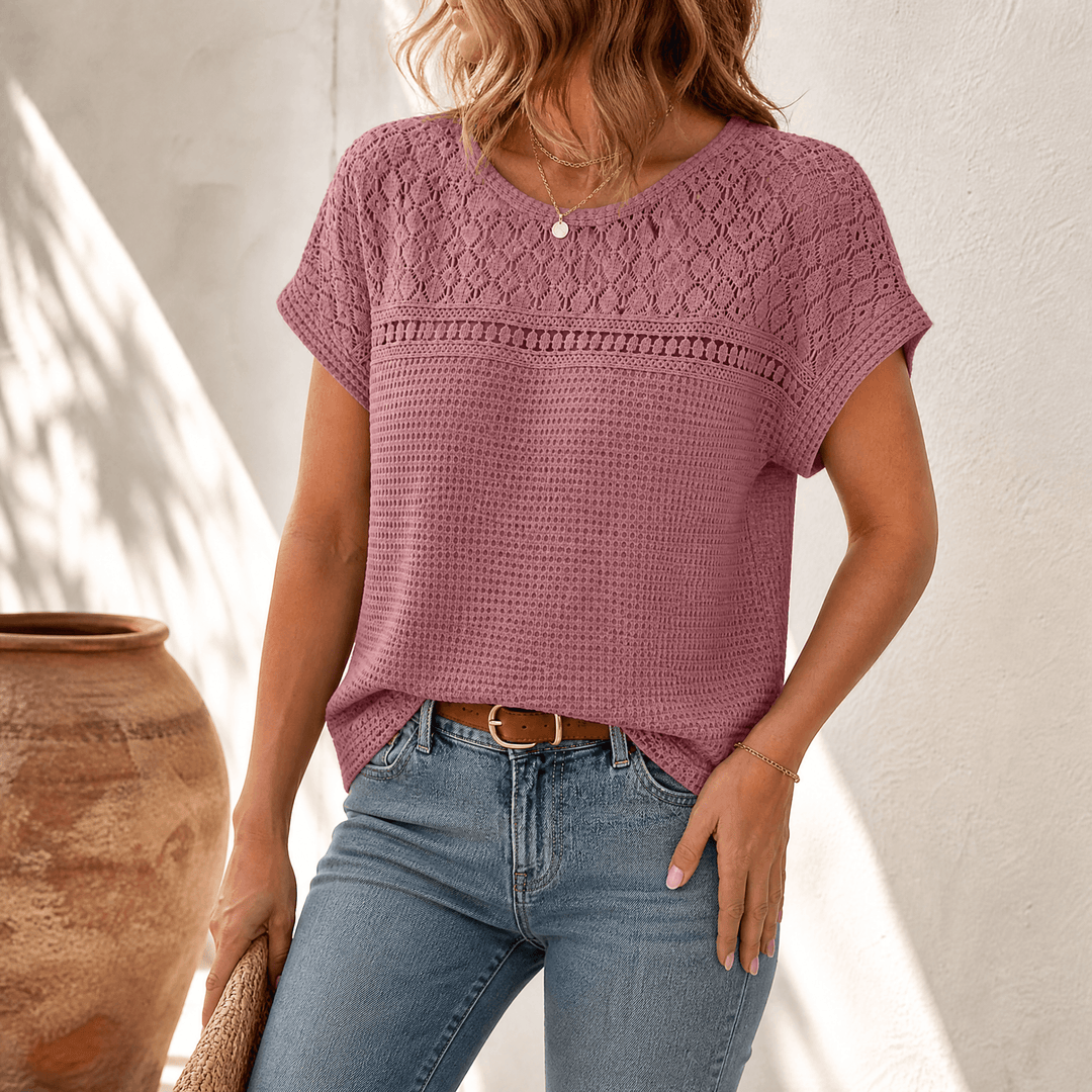 Close-up of a woman wearing a dusty pink open-weave summer top with round neckline.