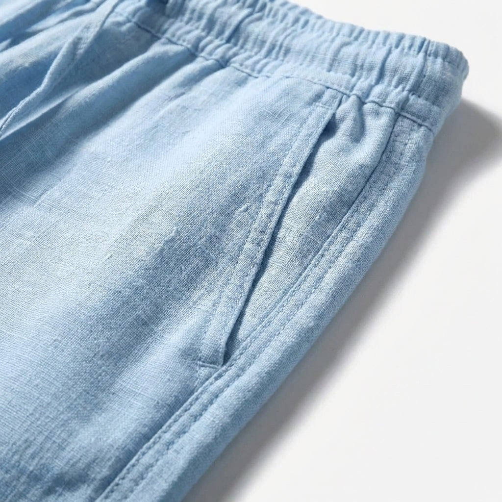 Close-up detail of the elastic waistband and pocket on light blue casual trousers