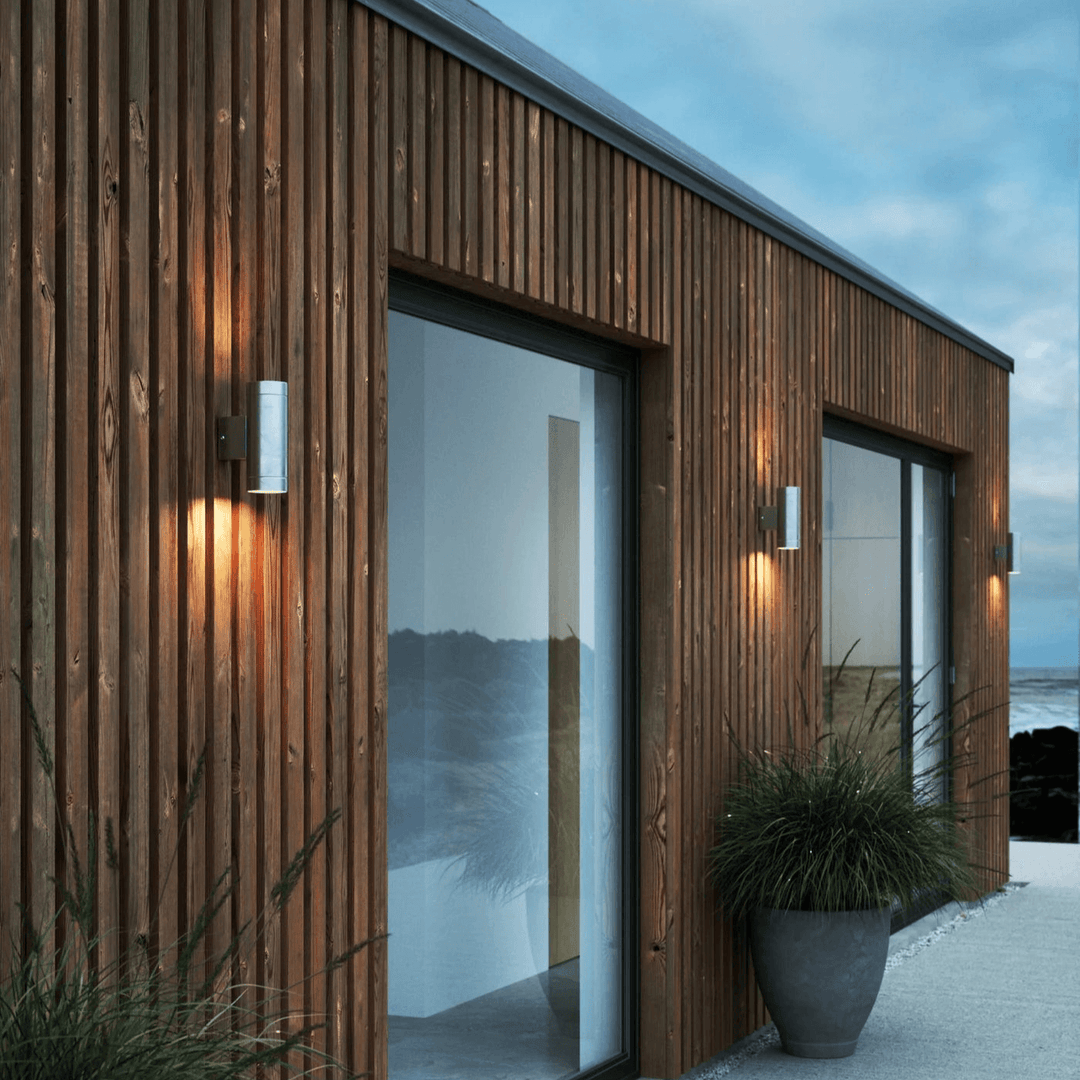 Outdoor wall lamp mounted on a modern wooden slatted exterior wall casting warm light