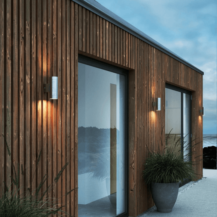 Outdoor wall lamp mounted on a modern wooden slatted exterior wall casting warm light