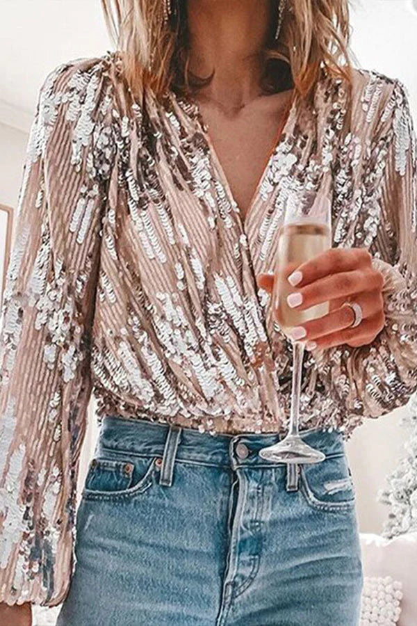 Woman wearing a glamorous sequin blouse with balloon sleeves holding a glass