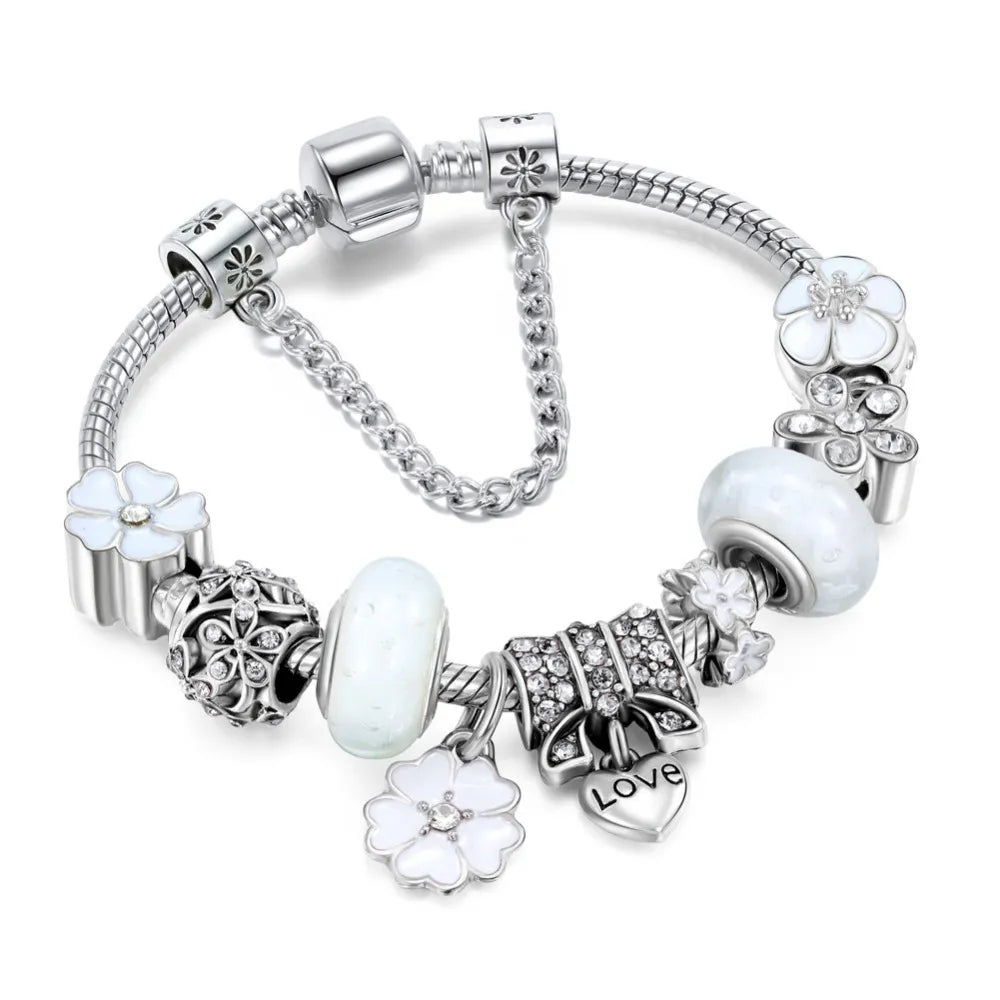 Close-up of women's silver charm bracelet featuring delicate flower design