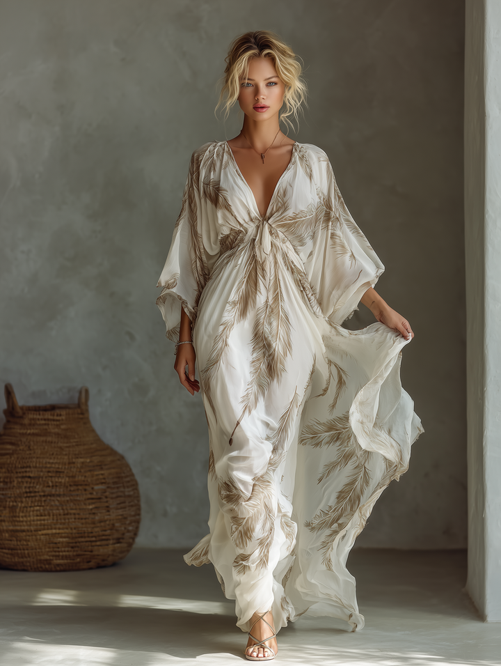 Full-body view of a model in a cream and golden feather print maxi dress with dramatic batwing sleeves.