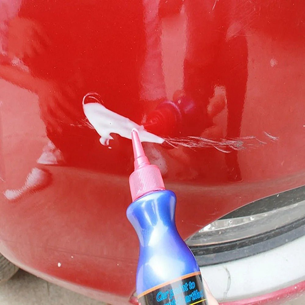 Applying white scratch removal polish compound directly onto a red car scratch
