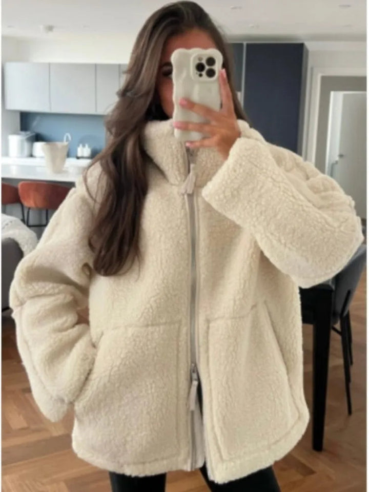 Woman wearing a white teddy fleece jacket indoors