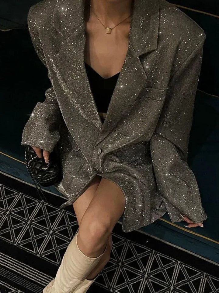 Woman wearing a sparkling silver sequin blazer sitting down